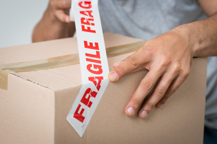 A man taping a box with a fragile tape