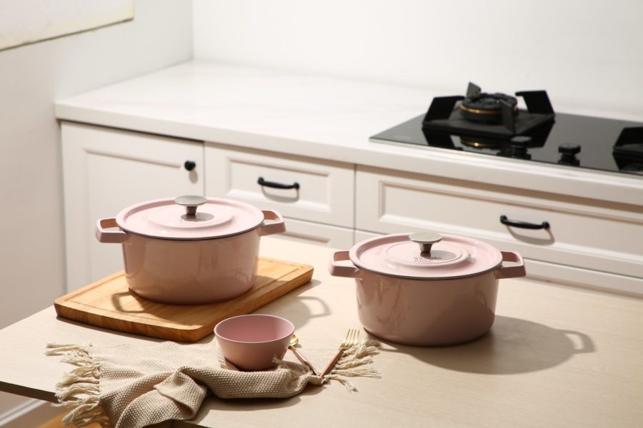 Two pink ceramic cooking pots on a white table